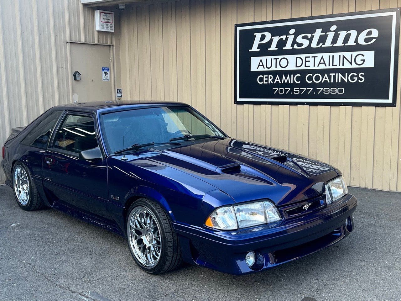 Blue Ford Mustang parked outside detailing shop