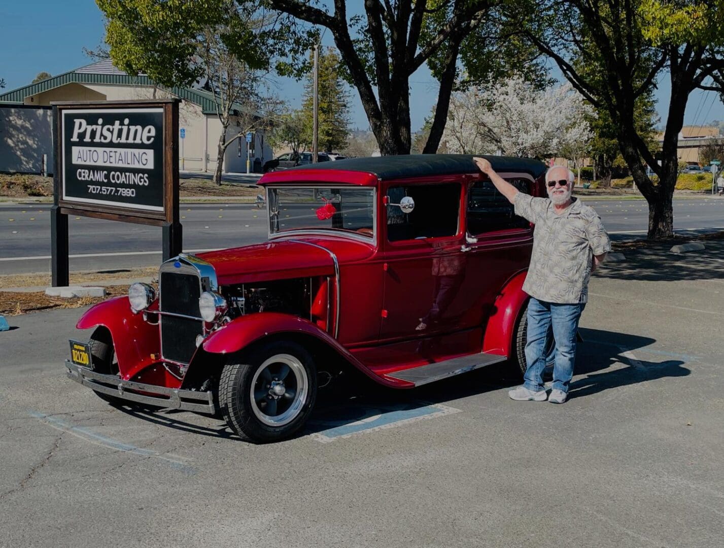 Man posing beside red classic car