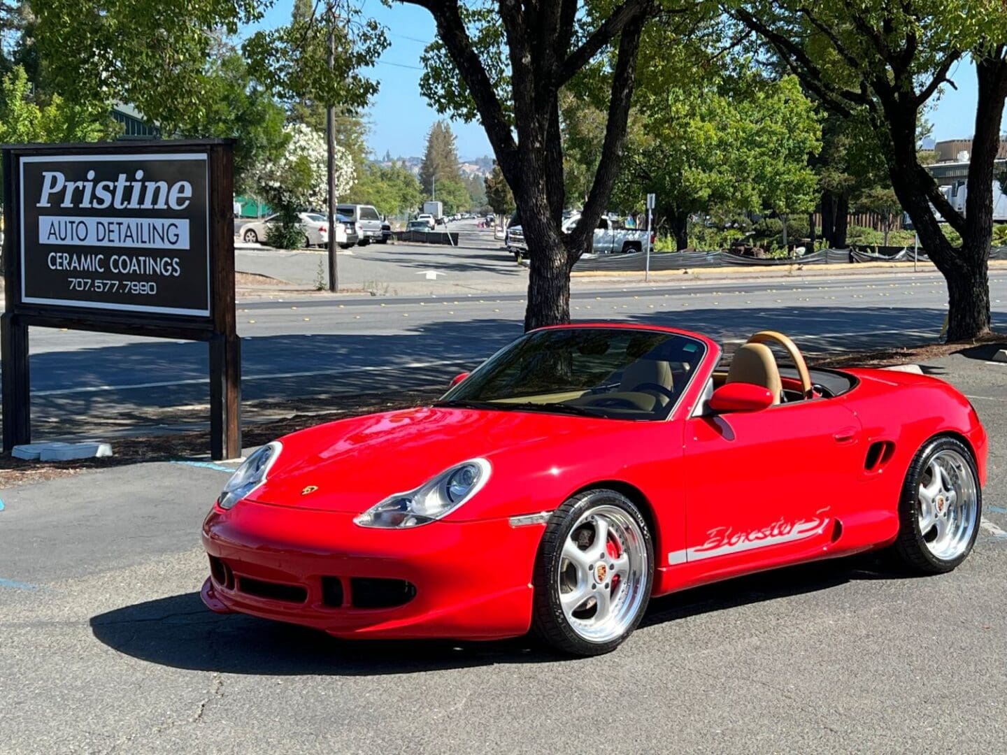 Red Porsche Boxster convertible parked by sign